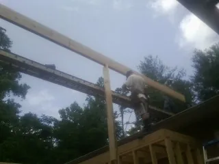 Carpenter setting a ridge beam over a new addition frame — Ice Dam Removal by Roofing Brothers in Mont Belvieu