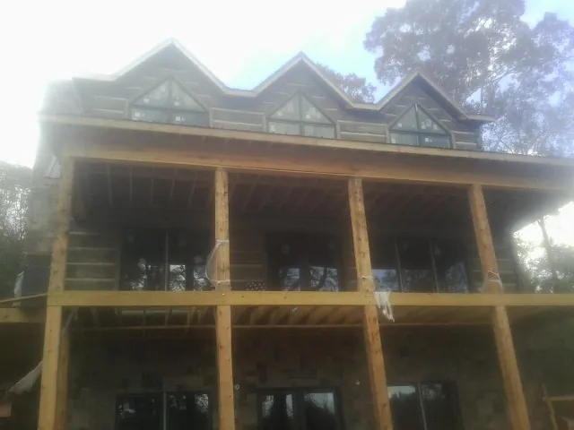 Dormers and porch framing on a large log home under construction — Roof Coating work by our crew in Mont Belvieu