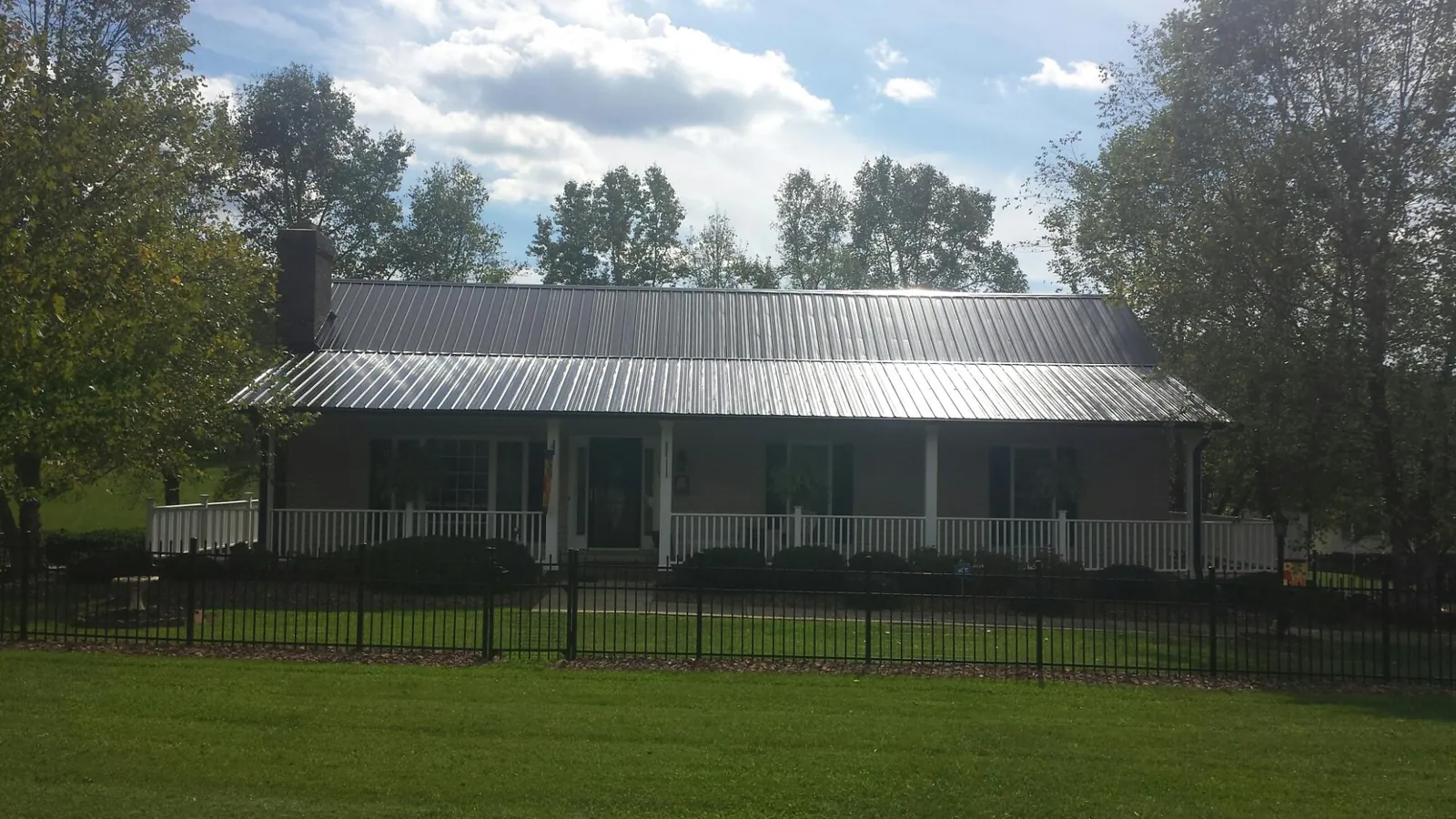 Gray metal roof on a brick ranch with a full width front porch — Gutter Guard Installation work by our crew in Mont Belvieu