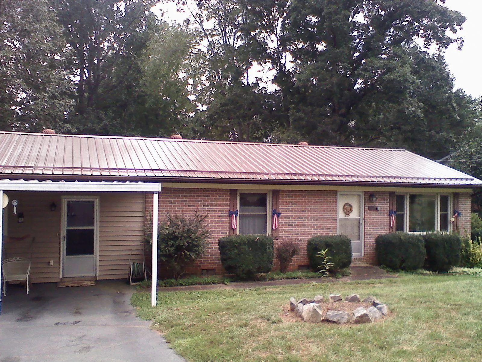 Bronze metal roof and carport on a brick ranch home — Roof Repair work by our crew in Mont Belvieu