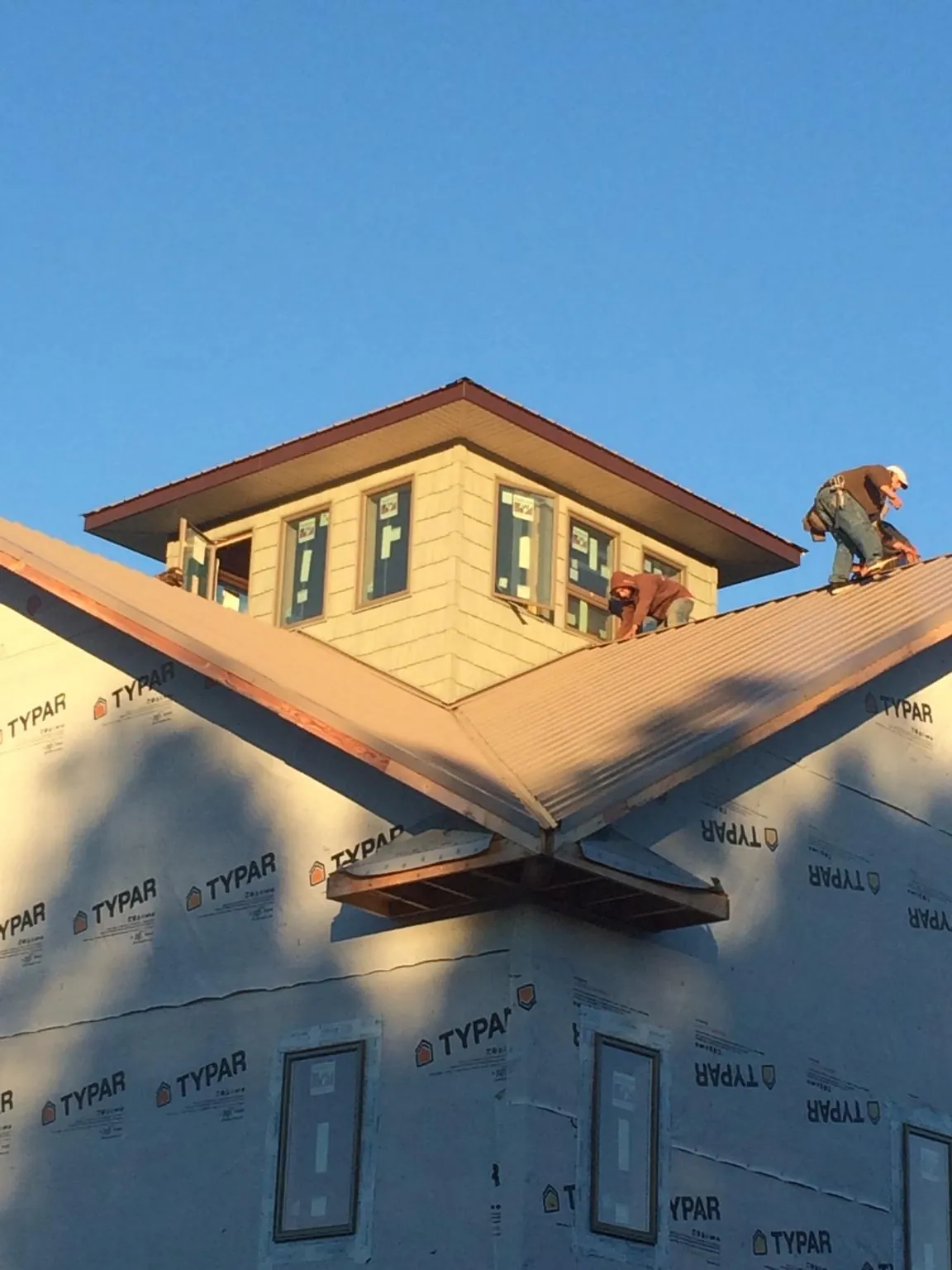 Roofers working around a rooftop cupola on a new metal roof at sunset — Roof Waterproofing in Mont Belvieu by Roofing Brothers